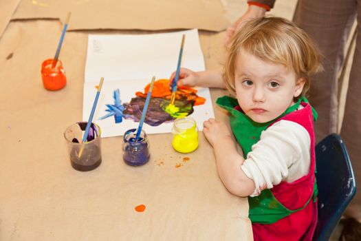 Cute little baby girl having fun painting at art class