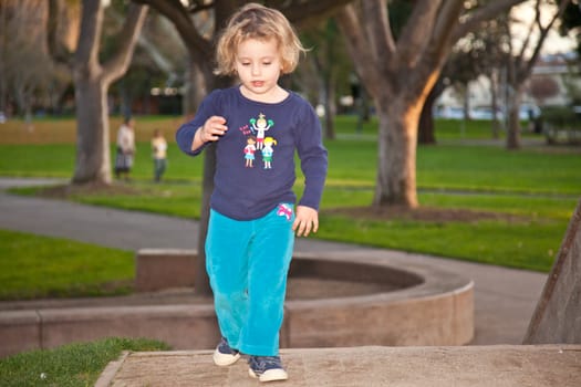 Cute little European girl having fun on playground in a park.