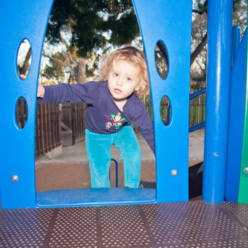 Cute little European girl having fun on playground in a park.