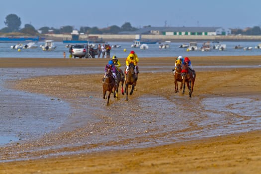 SANLUCAR DE BARRAMEDA, CADIZ, SPAIN - AUGUST 11: Unidentified riders at the start of race horses on Sanlucar de Barrameda beach on August 11, 2011 in Sanlucar de Barrameda, Cadiz, Spain.