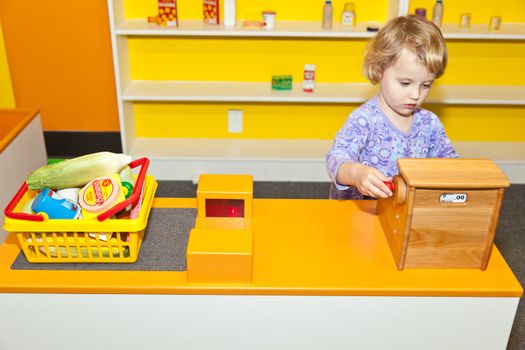 Cute little European toddler girl having fun at indoor playground.