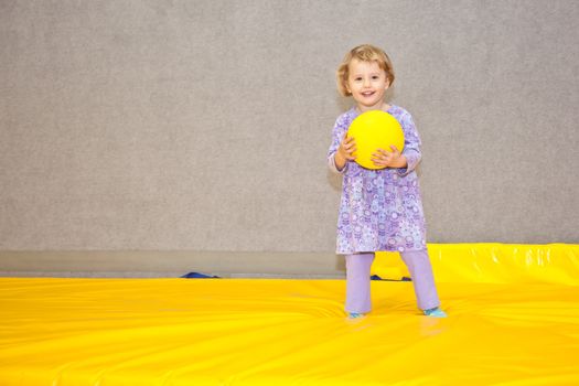Cute little European toddler girl having fun at indoor playground.