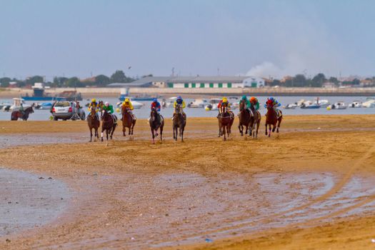 SANLUCAR DE BARRAMEDA, CADIZ, SPAIN - AUGUST 11: Unidentified riders race horses on Sanlucar de Barrameda beach on August 11, 2011 in Sanlucar de Barrameda, Cadiz, Spain.