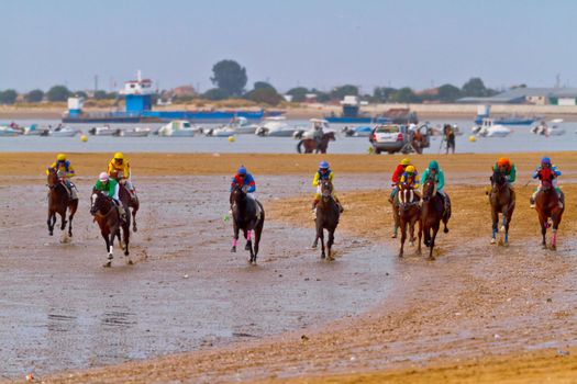 SANLUCAR DE BARRAMEDA, CADIZ, SPAIN - AUGUST 11: Unidentified riders race horses on Sanlucar de Barrameda beach on August 11, 2011 in Sanlucar de Barrameda, Cadiz, Spain.