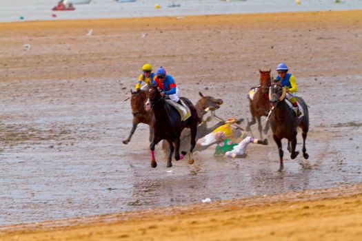 SANLUCAR DE BARRAMEDA, CADIZ, SPAIN - AUGUST 11: Unidentified riders race horses on Sanlucar de Barrameda beach on August 11, 2011 in Sanlucar de Barrameda, Cadiz, Spain.