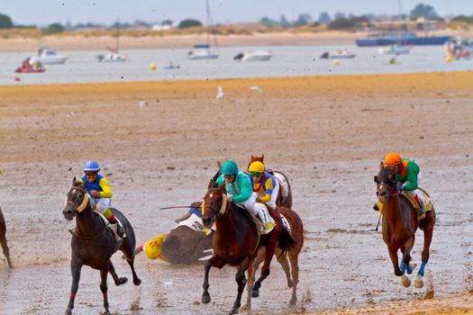 SANLUCAR DE BARRAMEDA, CADIZ, SPAIN - AUGUST 11: Unidentified riders race horses on Sanlucar de Barrameda beach on August 11, 2011 in Sanlucar de Barrameda, Cadiz, Spain.