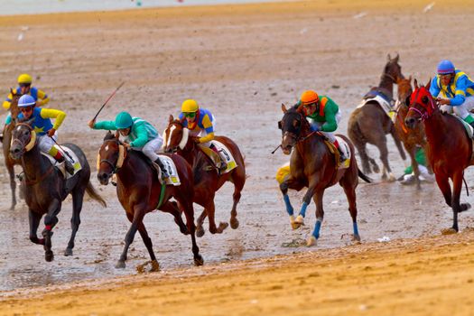 SANLUCAR DE BARRAMEDA, CADIZ, SPAIN - AUGUST 11: Unidentified riders race horses on Sanlucar de Barrameda beach on August 11, 2011 in Sanlucar de Barrameda, Cadiz, Spain.
