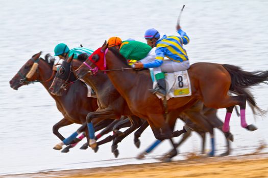 SANLUCAR DE BARRAMEDA, CADIZ, SPAIN - AUGUST 11: Unidentified riders race horses on Sanlucar de Barrameda beach on August 11, 2011 in Sanlucar de Barrameda, Cadiz, Spain.