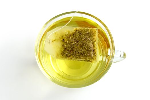 The bag of green herbal tea in a glass bowl with water, isolated on a white background