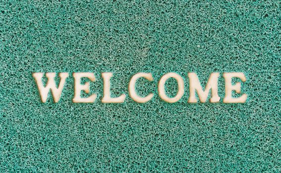 Green door mat with welcome written on it