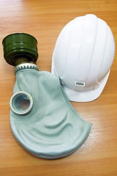 The white helmet and gas mask on the background of a wooden tabletop