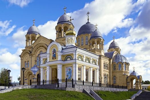 Holy Cross Cathedral, with gray zinc dome and the Chapel of St. Nicholas Monastery in the background of blue sky and white clouds (Verhoturie city of Sverdlovsk Region)
