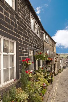 A Terrace of Old Mill Cottages on Haworth Yorkshire Main Street decrated with Hanging Baskets and Flowers