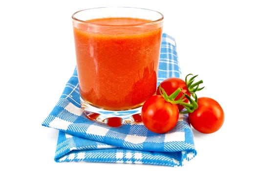 Tomato juice in a glass beaker, three small tomatoes on a blue checkered napkin isolated on a white background