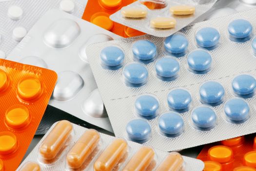 Pills of many shapes and colors grouped together