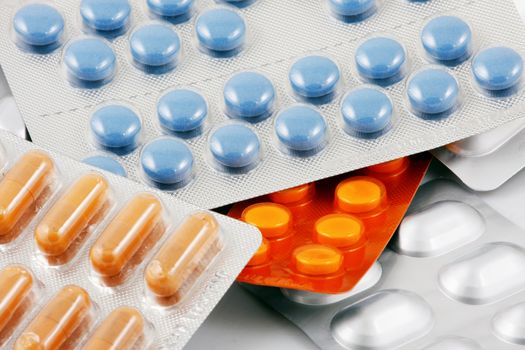 Pills of many shapes and colors grouped together