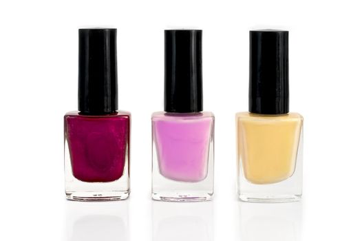 Three bottles with yellow, purple and pink nail polish isolated on white background