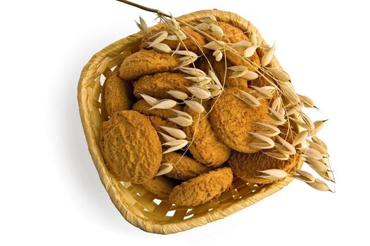 Oatmeal cookies in a wicker basket with a stalk of oats from above isolated on white background