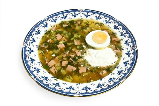 Okroshka with sour cream and sliced half an egg in a porcelain dish isolated on a white background