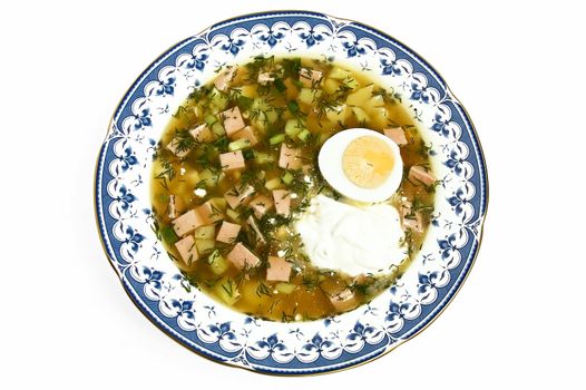 Okroshka with sour cream and sliced half an egg in a porcelain dish isolated on a white background