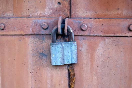 The old steel door closed on the hanging metal lock