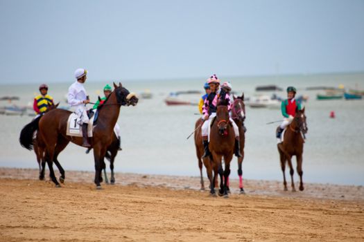 SANLUCAR DE BARRAMEDA, CADIZ, SPAIN - AUGUST 07: Unidentified riders at the start of race horses on Sanlucar de Barrameda beach on  August 07, 2010 in Sanlucar de Barrameda, Cadiz, Spain.