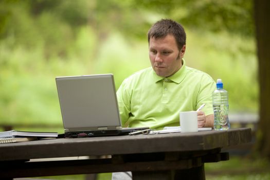 Man in green shirt at open space office in nature