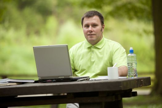 Man in green shirt at open space office in nature