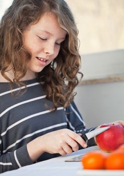 Cute teen girl cutting in the kitchen and cutting an apple with a knife