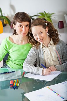 Teenager girl sitting together with her mother and showing her homework