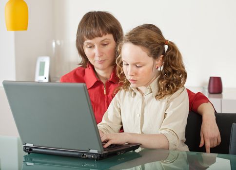 Mother and teenager girl with laptop computer together at home