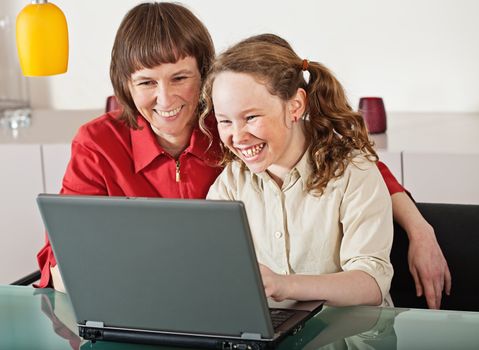 Mother and teenager girl with laptop computer together at home