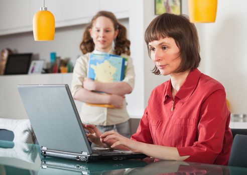 Mother and teenager girl with laptop computer together at home