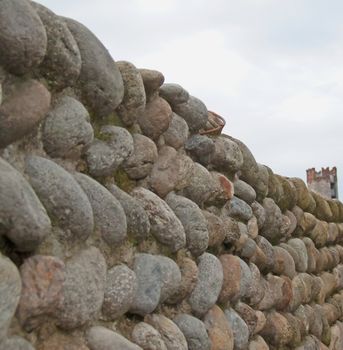 A wall of stone of a castle, with far tower