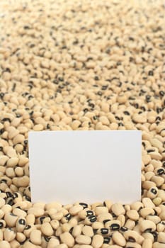 Raw black-eyed peas (cowpeas) with a blank card (Selective Focus, Focus on the card)