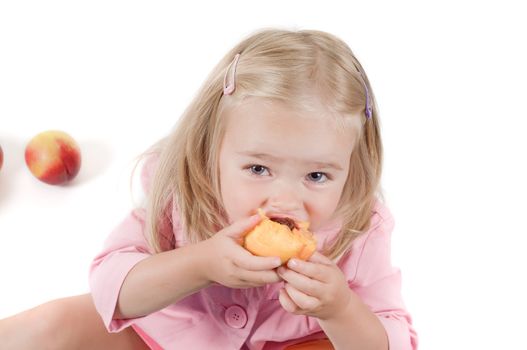 Shot of little girl eating peach in studio