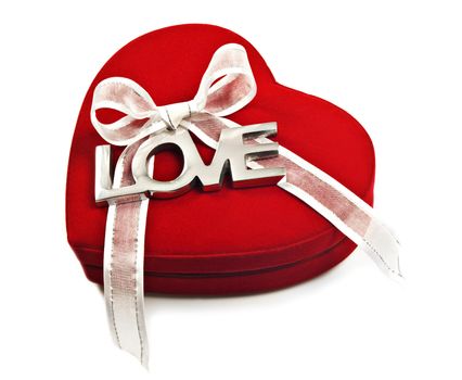 a Red heart with the word love spelled out in silver on a white ribbon