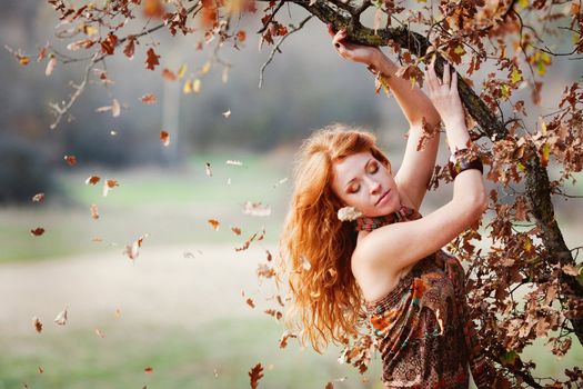 The red-haired girl in autumn leaves 
outdoor shot