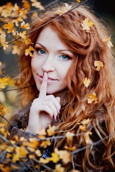 The red-haired girl in autumn leaves 
outdoor shot