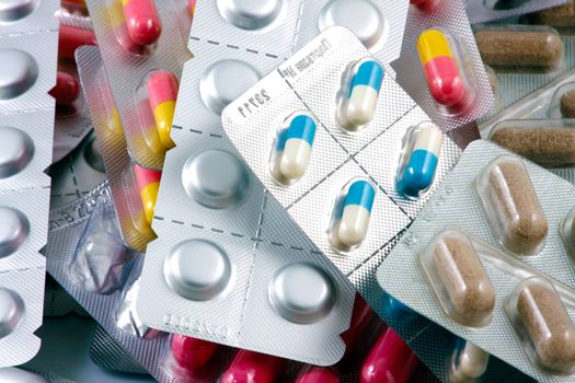 Pills of many shapes and colors grouped together