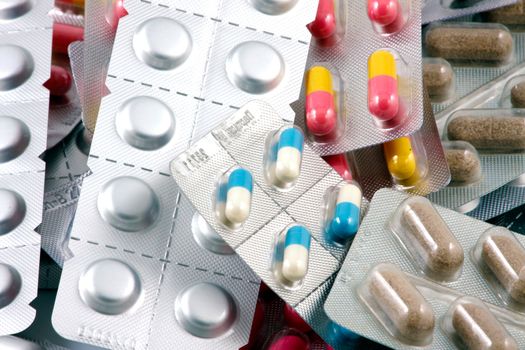 Pills of many shapes and colors grouped together