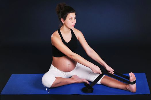 Beautiful pregnant  young woman practicing yoga on black