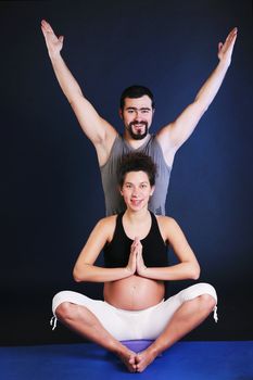 Beautiful pregnant  young woman practicing yoga with husband