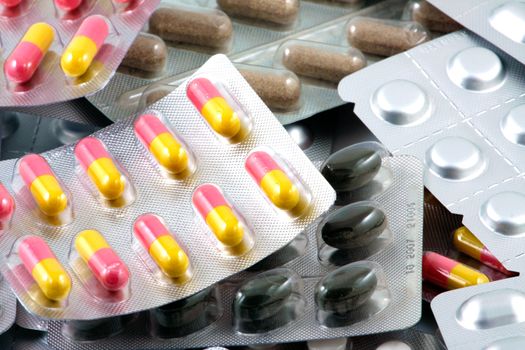 Pills of many shapes and colors grouped together