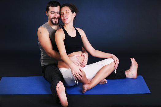 Beautiful pregnant  young woman practicing yoga with husband