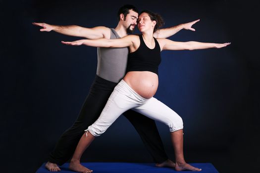 Beautiful pregnant  young woman practicing yoga with husband