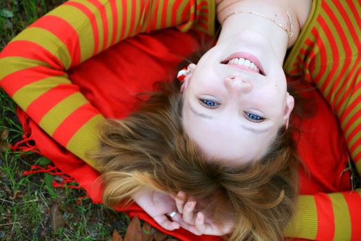 portrait of a girl in a bright colored striped sweater lying on the grass