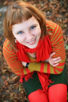 portrait of a girl in a bright colored striped sweater lying on the grass
