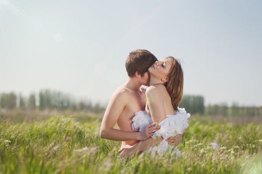 beautiful young pair kissing and hugging on green grass