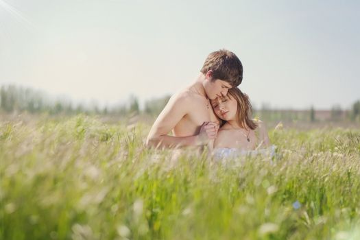 beautiful young pair kissing and hugging on green grass